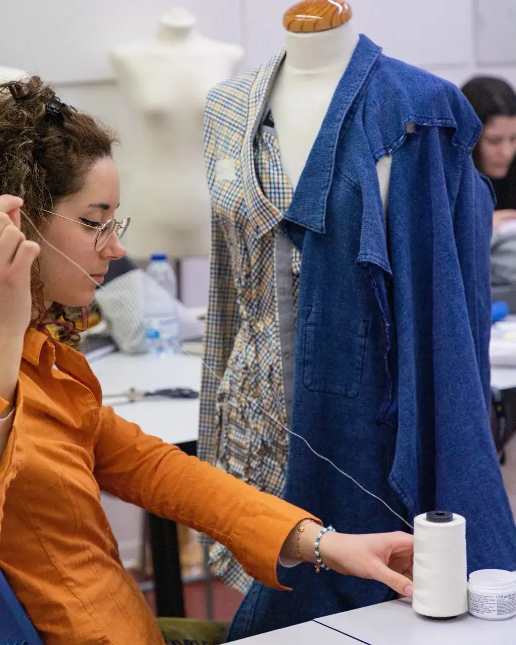 Estudiante del Curso de Patronaje y Costura de ESDI cosiendo una prenda sobre maniquí con diferentes tejidos.