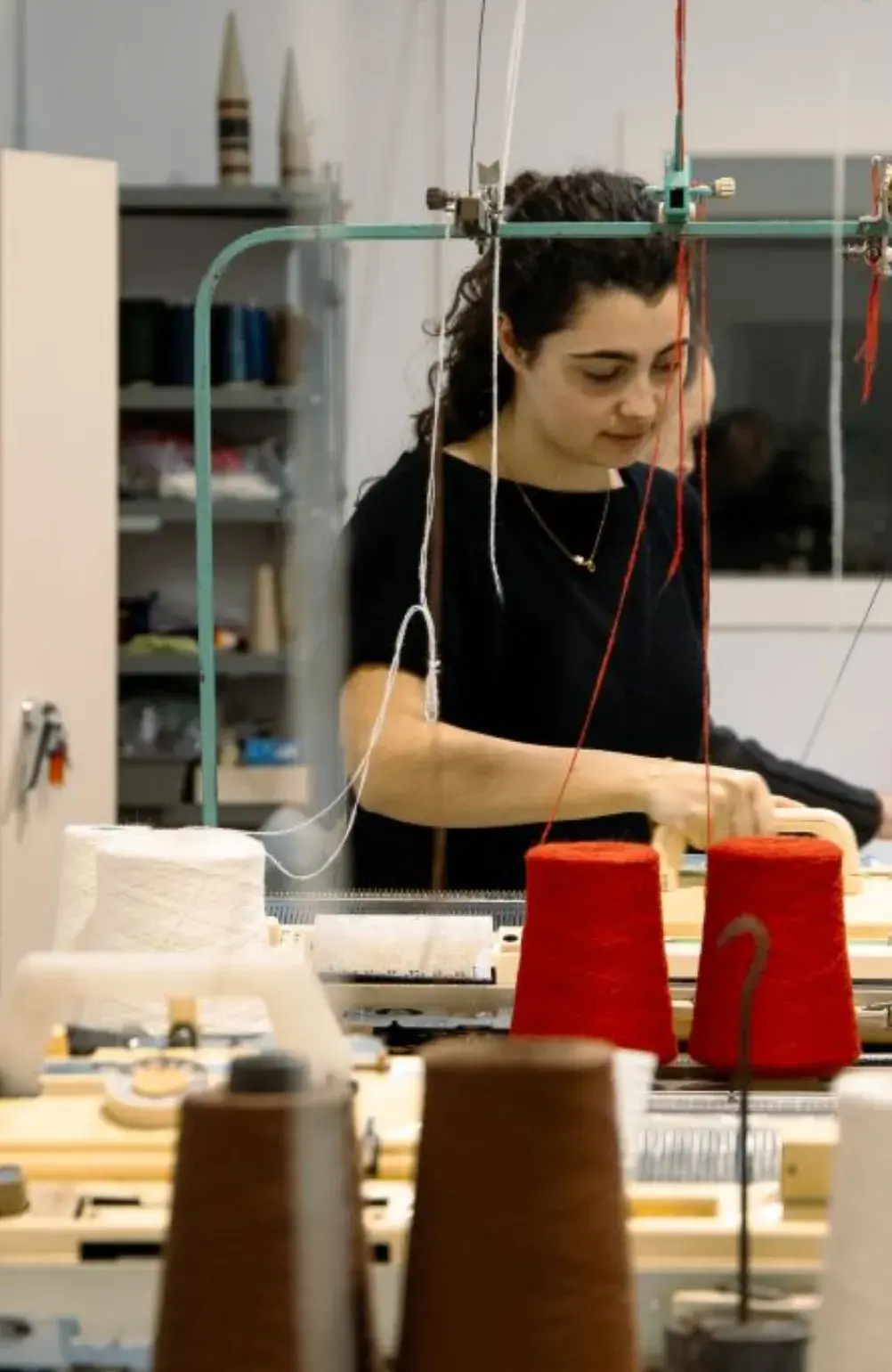 Estudiante del Curso de Patronaje y Costura de ESDI trabajando con hilos y maquinaria textil en el taller.
